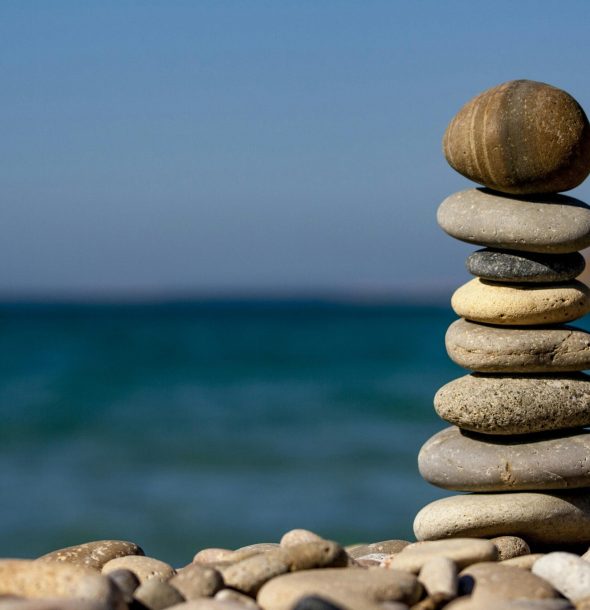 A stack of balanced stones on a beach with a tranquil ocean backdrop for meditation and zen.